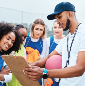 Coach with young girls on a sporting field