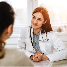 Young female doctor sitting across table talking to patient